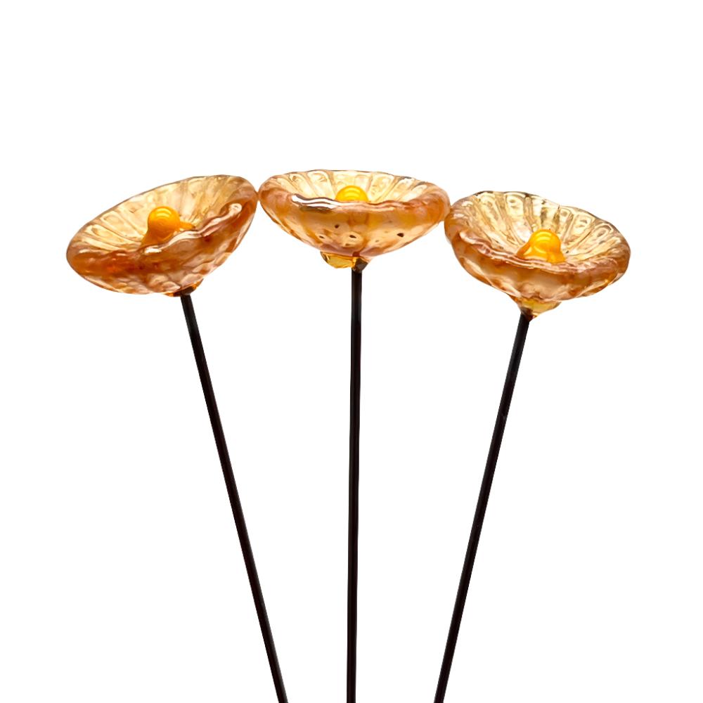 three speckled amber glass daisies with yellow centres on metal stakes