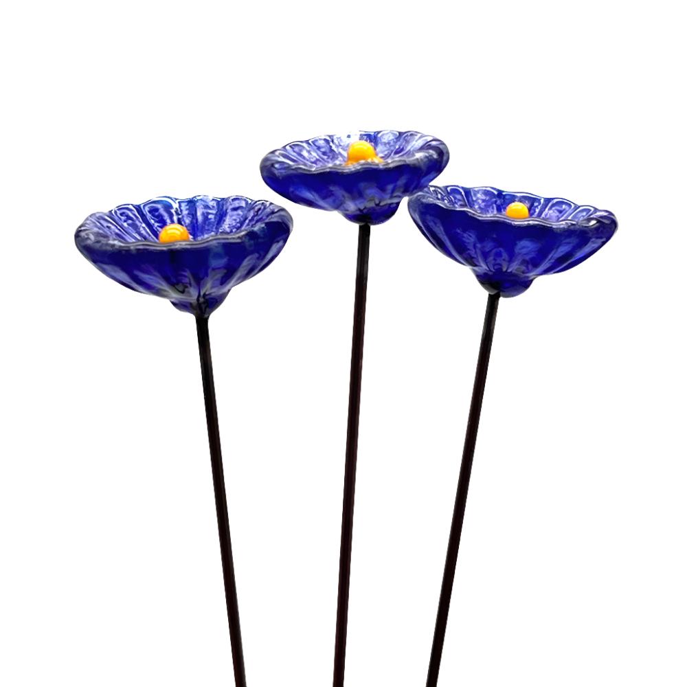 three speckled dark blue glass daisies with yellow centres on metal stakes