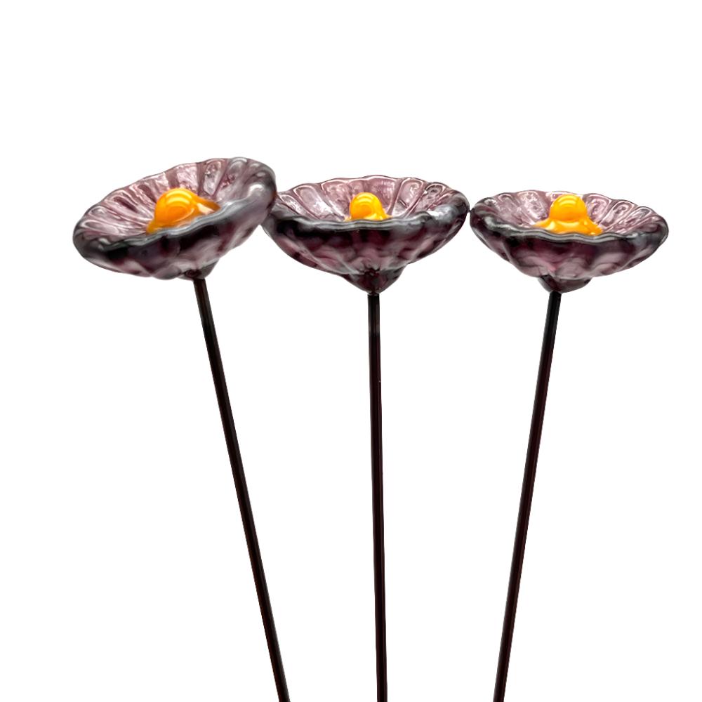 three speckled p glass daisies with yellow centres on metal stakesrple