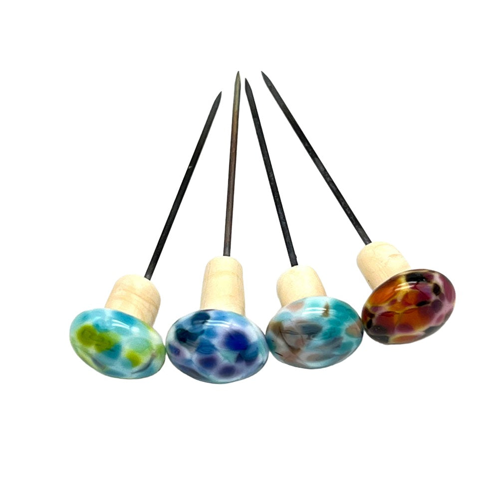 Top view of four speckled mushroom pins: A top-down perspective showing the colorful speckled caps of four handmade glass mushroom pins arranged neatly.