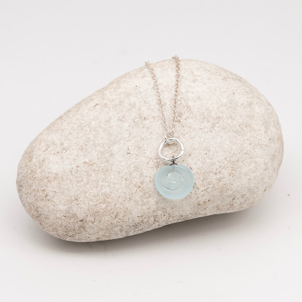 pale blue glass swirl charm necklace on a pale grey rock