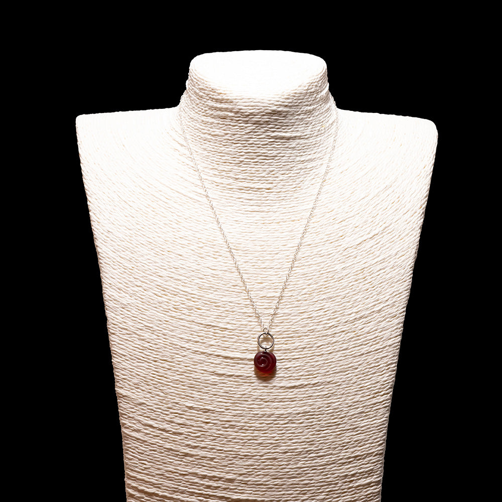 red glass swirl charm necklace with sterling silver chain shown on a white mannequin bust