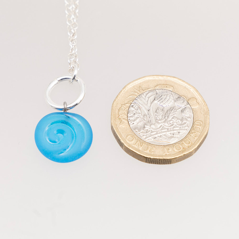 Swirl necklace shown with pound coin for scale. The glass charm is roughly half the height of the coin.