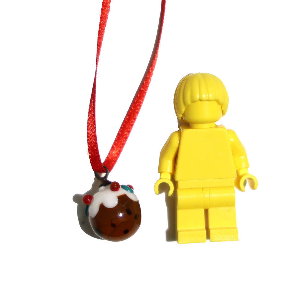 Tiny glass christmas pudding decoration shown with a lego figure for scale.