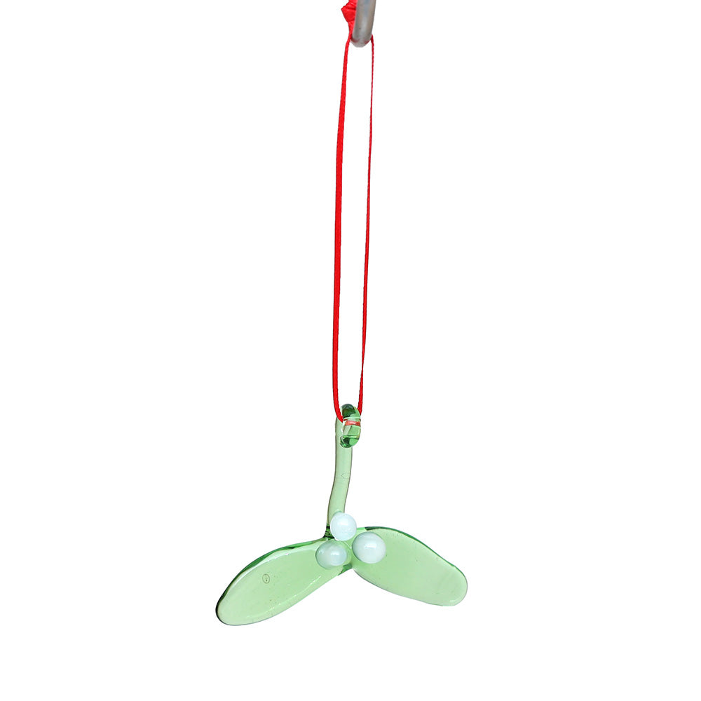 Tiny green glass mistletoe decoration hanging on a red ribbon