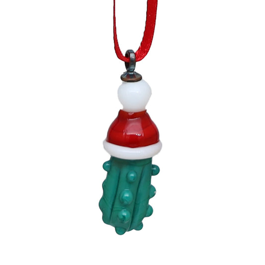 Close up of textured green glass pickle wearing a red and white santa hat