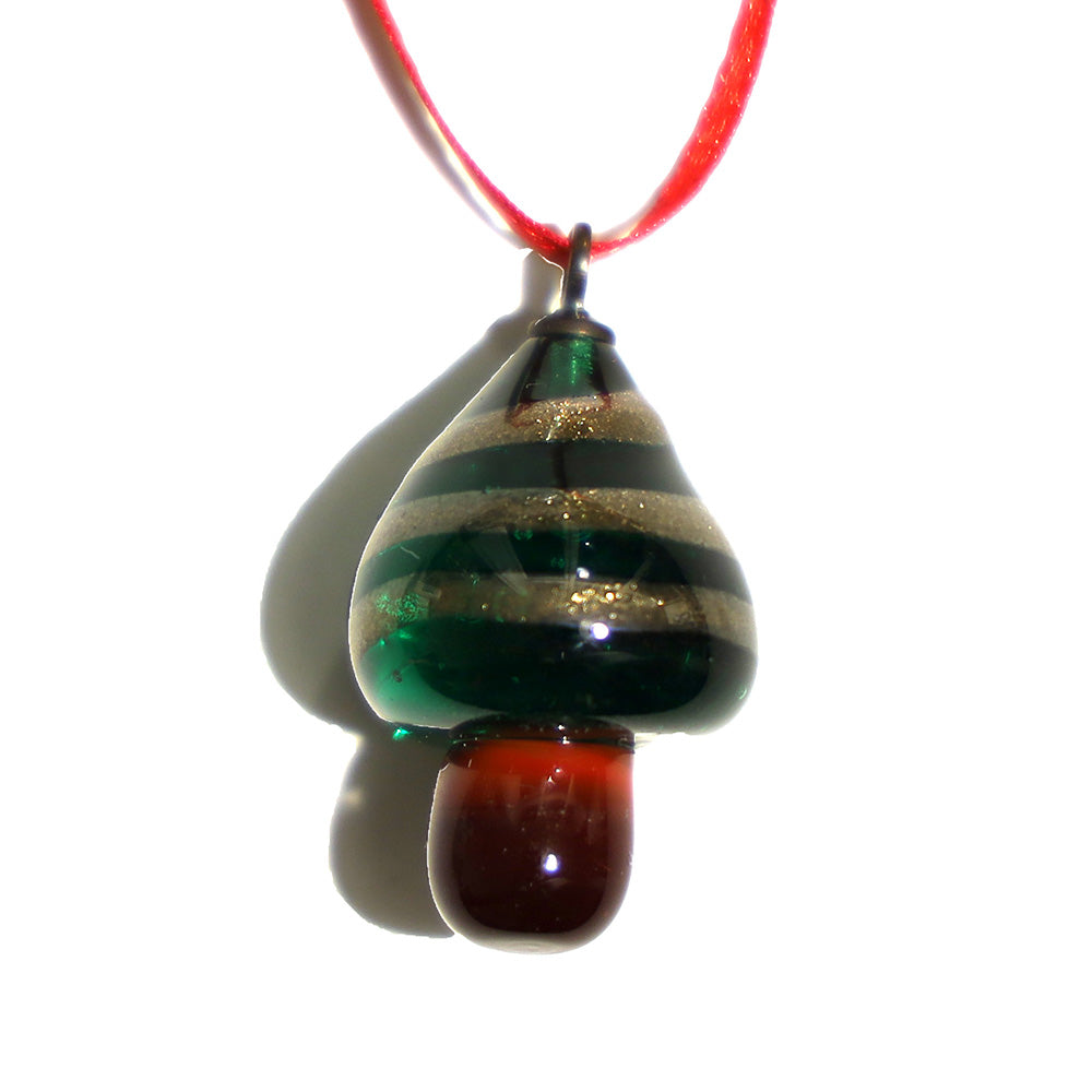 tiny sparkly tree decoration ona red ribbon. Tree is transparent green glass and is decorated weith a switl of sparkly gold glass.