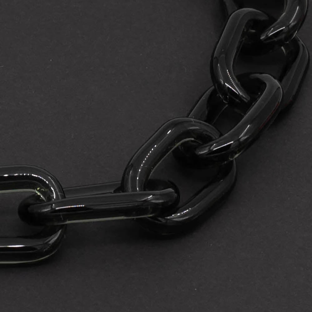 Close up of transparent glass chain links photographed on a dark background