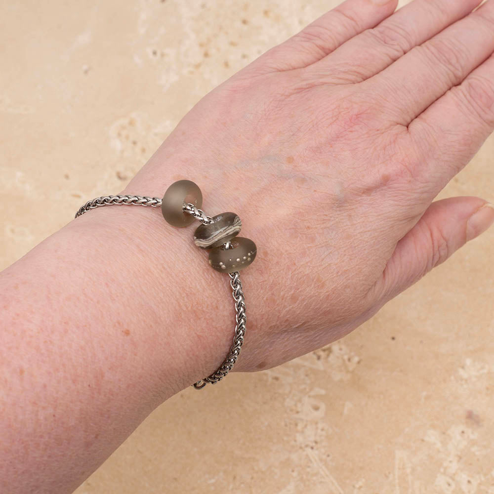 Bracelet with three frosted grey glass beads on a stainless steel chain bracelet on Joy's wrist