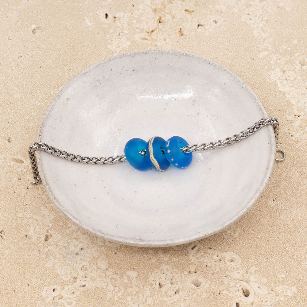 Small white ceramic dish with three frosted turquoise glass beads on a stainless steel chain