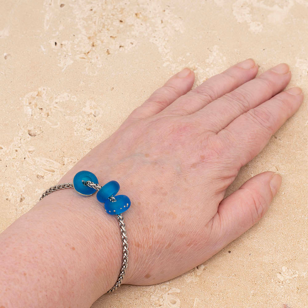 Bracelet  on Joy's wrist with three frosted turquoise glass beads on a stainless steel chain