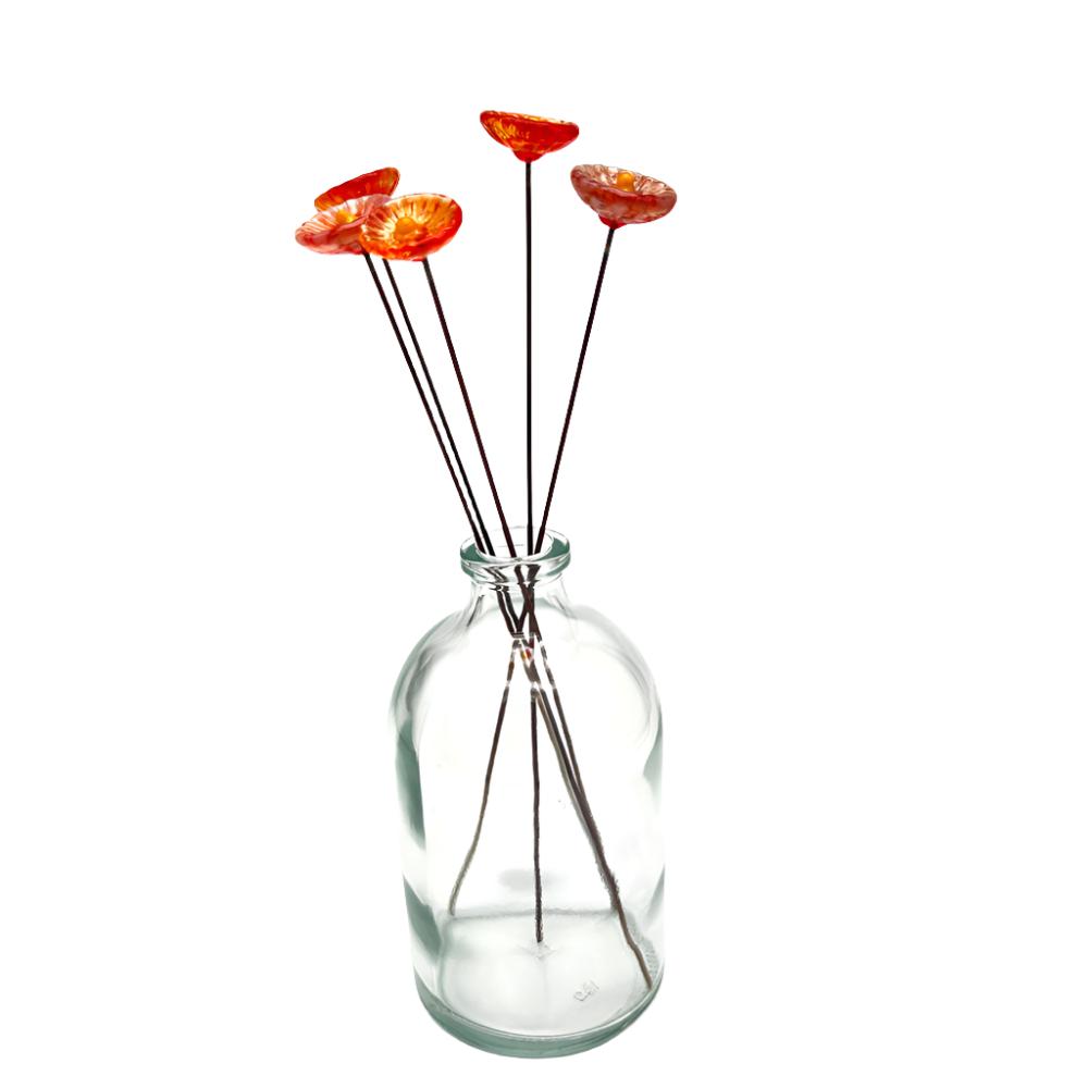 clear glass vase with five glass daisies in reds and oranges