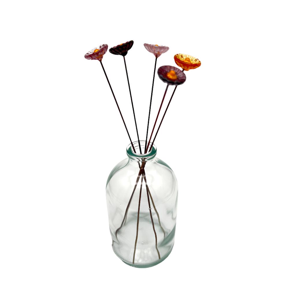 clear glass vase with five glass daisies in purples, pinks and amber